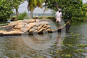 Allepey, Kerala, India Ã¢â¬â March 31, 2015: Indian man transport dwell with rice for boats. backwaters canoe in state